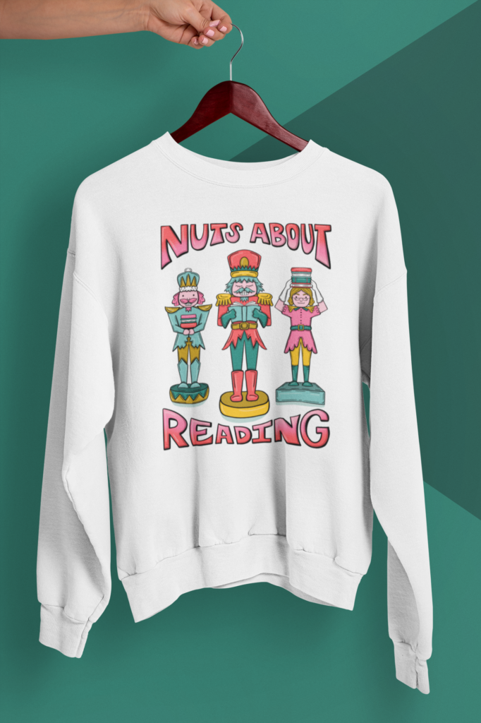 White sweatshirt with colorful 'Nuts About Reading' nutcracker illustration, festive bookish Christmas apparel.